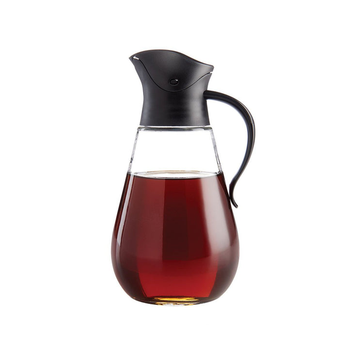 Glass carafe with black lid and handle filled with liquid on a white background