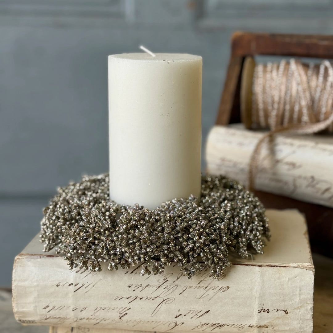 White candle on a decorative wreath placed on vintage books with a rustic background