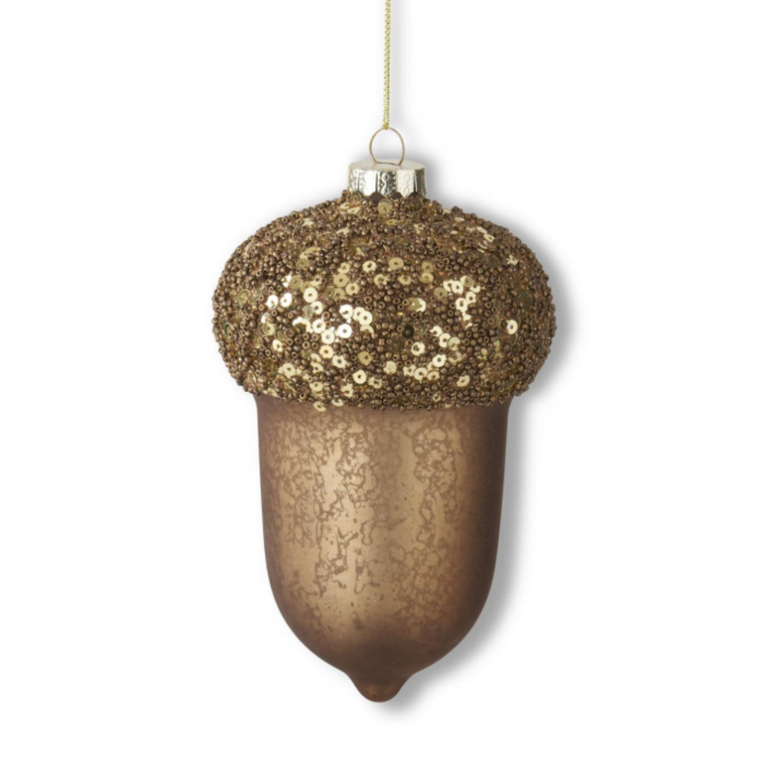 An acorn-shaped Christmas ornament with a textured metallic bronze body and a glittering gold sequined cap, hanging from a gold string against a white background.