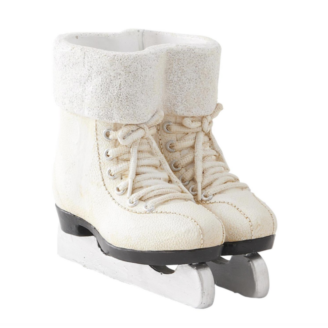 A pair of miniature ice skates with cream-colored faux-leather boots, fluffy white faux-fur trim around the cuffs, and metal blades, shown against a plain white background.