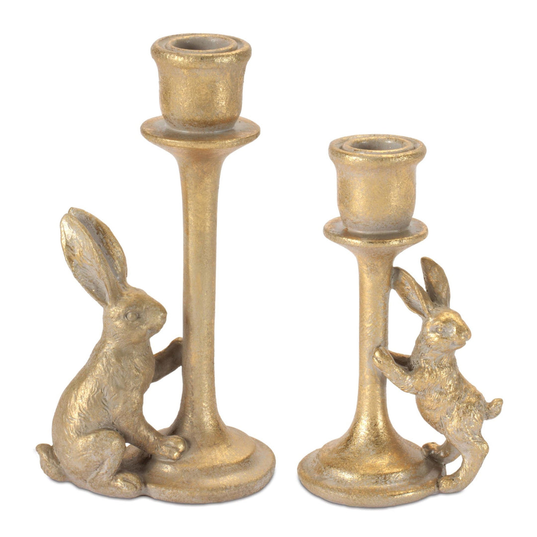 Two gold candle holders with rabbit designs on a white background