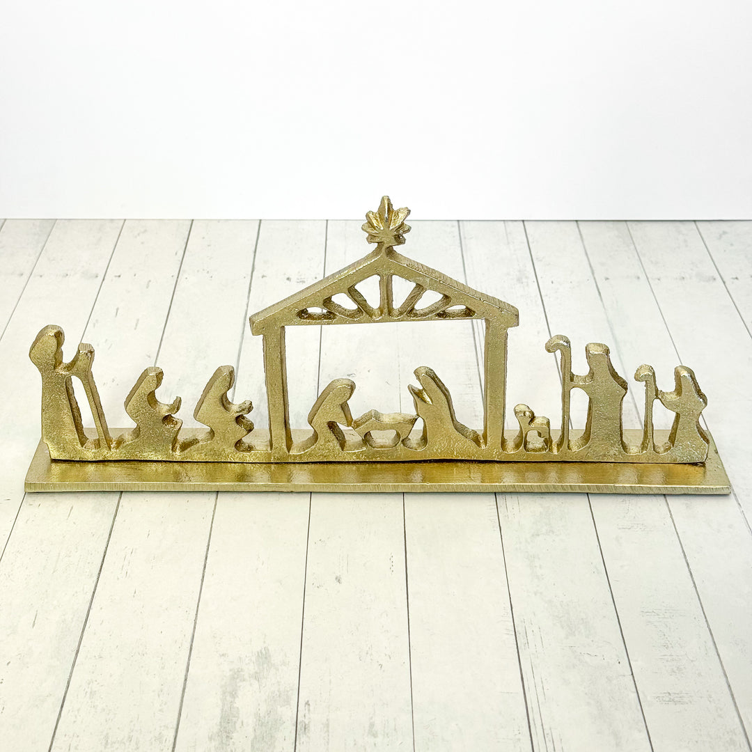 Gold nativity scene sculpture on a white wooden floor