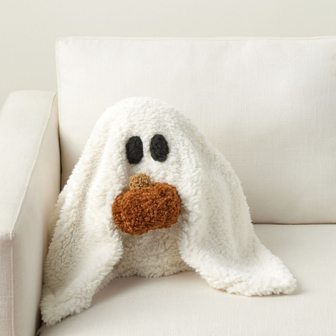 White plush ghost toy with black eyes and brown nose on a white couch