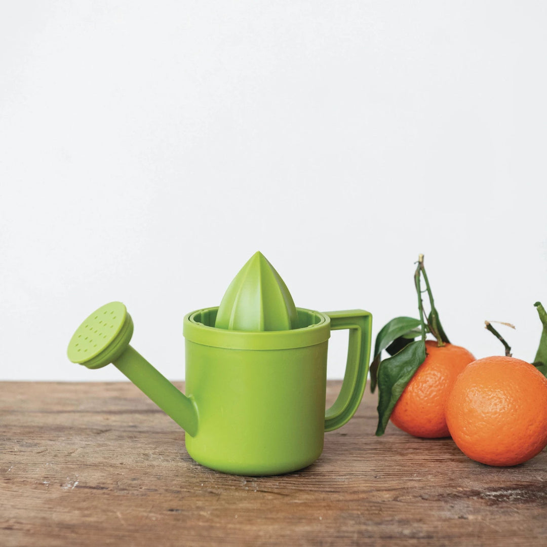 Green citrus juicer on a wooden surface with oranges