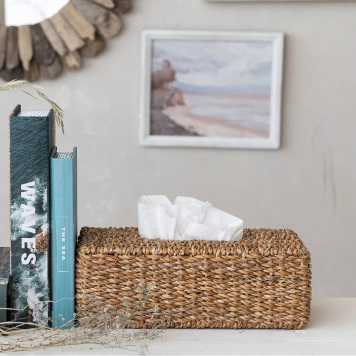Decorative mirror with natural wood elements, books, and a woven basket on a shelf.
