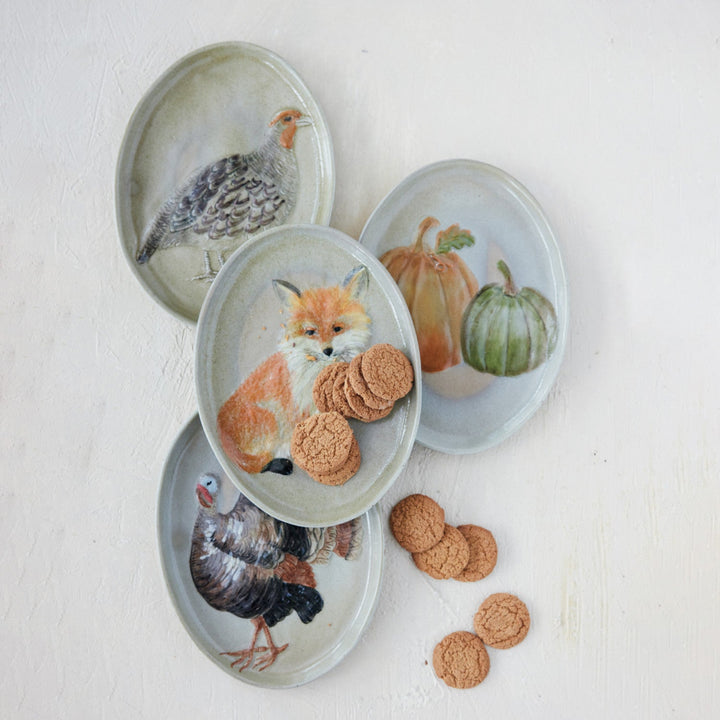 Set of four decorative plates with animal and nature-themed designs on a light background.