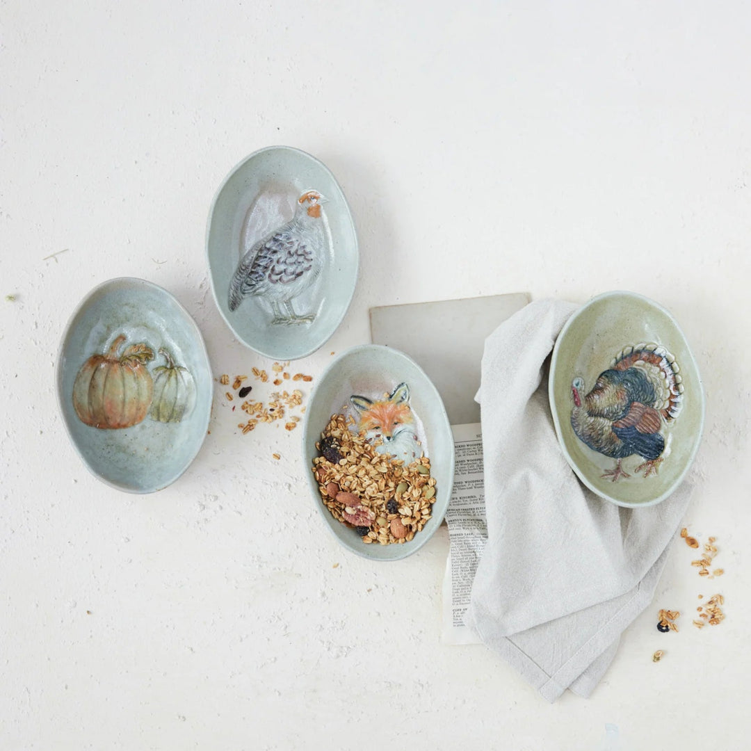 Set of four ceramic dishes with animal illustrations on a light surface.