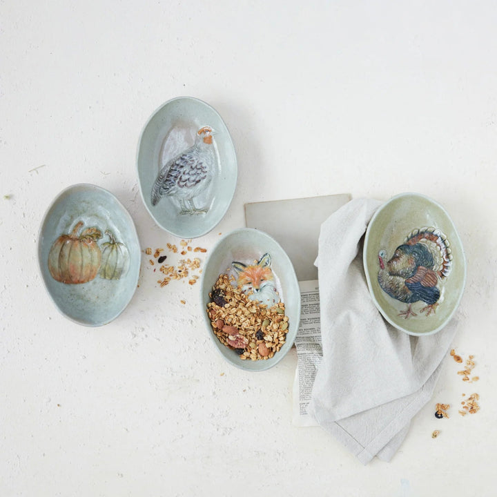 Set of four ceramic dishes with animal illustrations on a light surface.