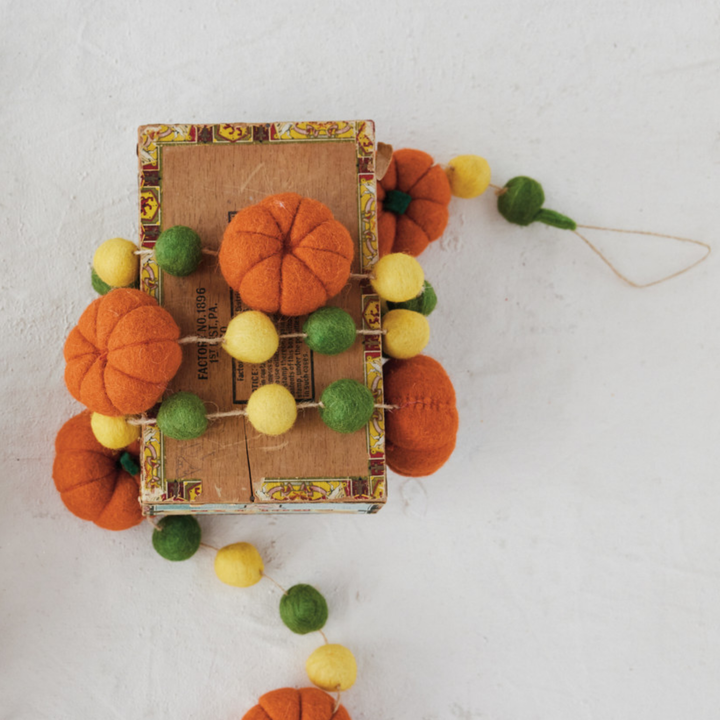 Decorative garland with pumpkins and colorful balls on a textured surface