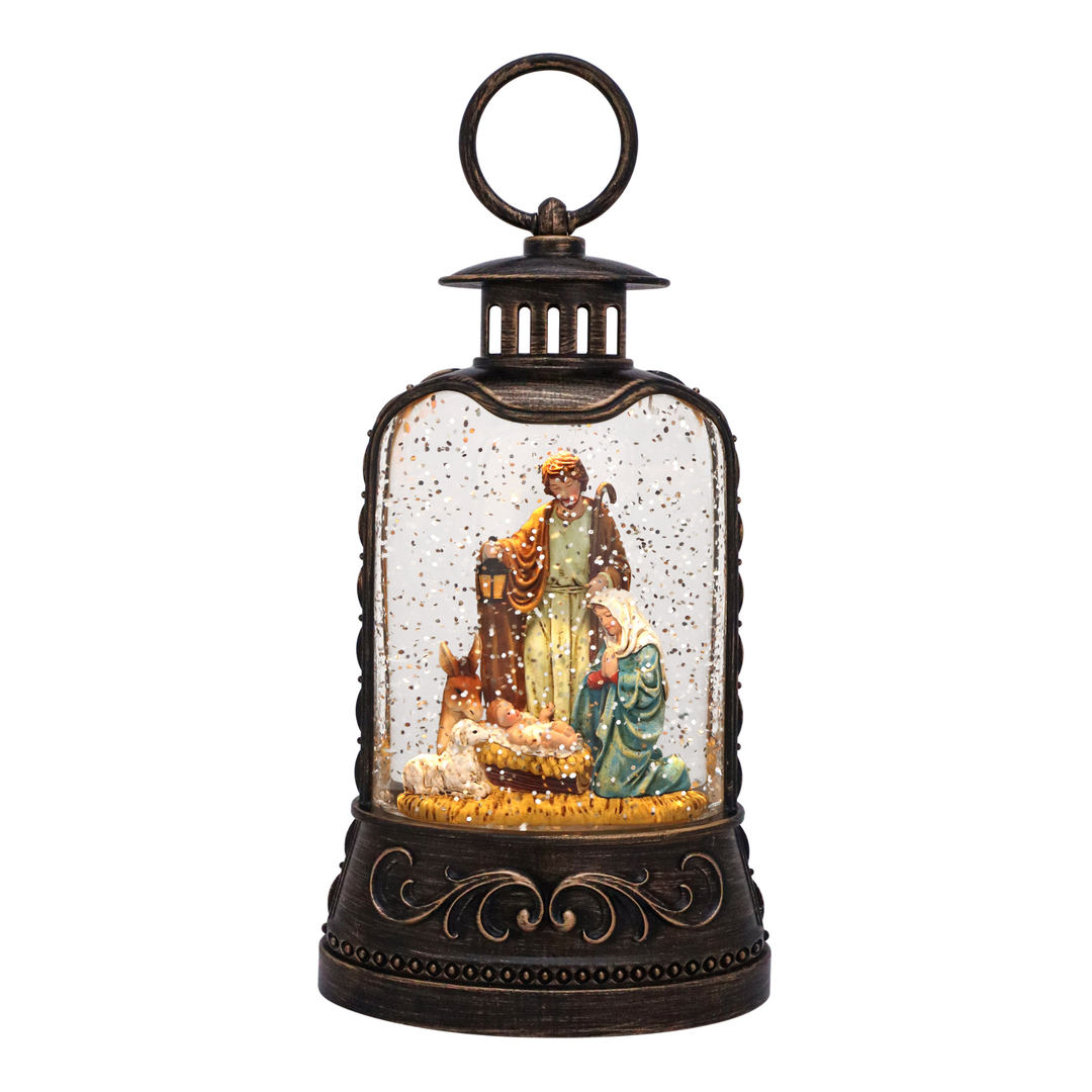 A decorative lantern-style Christmas ornament featuring a nativity scene under a clear glass dome with a dark bronze metal frame and handle, shown on a plain white background.
