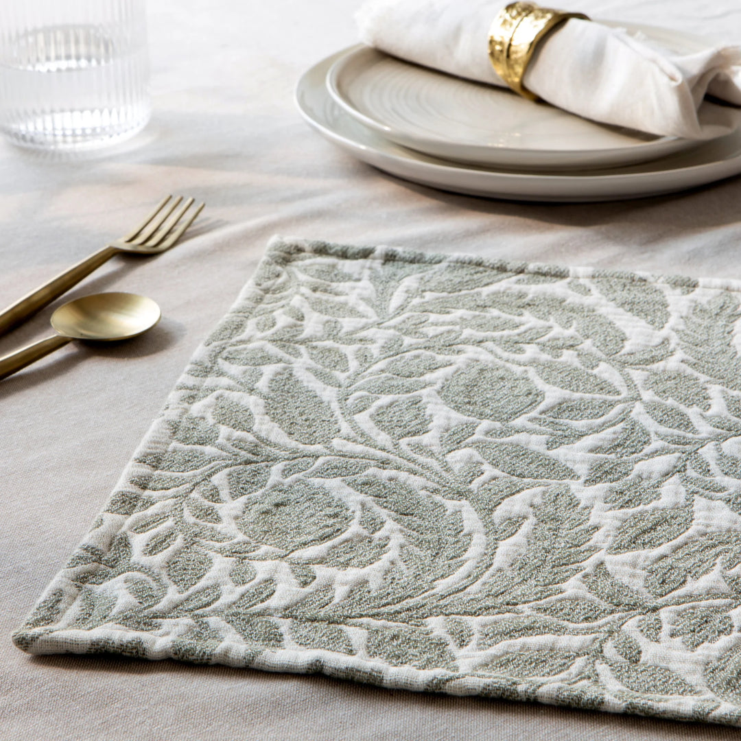 Decorative placemat with intricate pattern on a table setting with plates and cutlery.