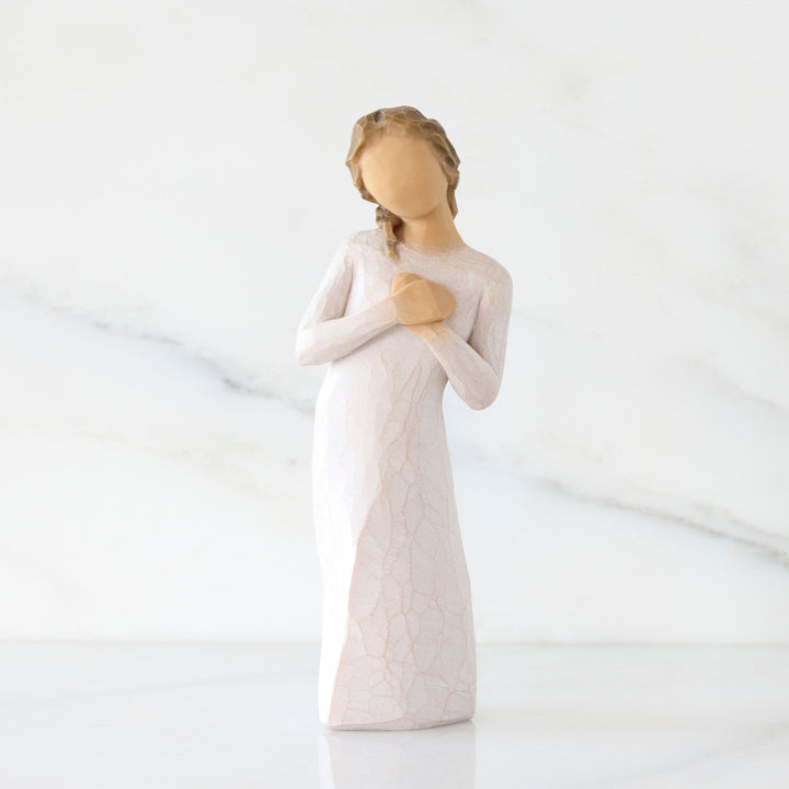White ceramic figurine of a woman holding her hands together on a white background