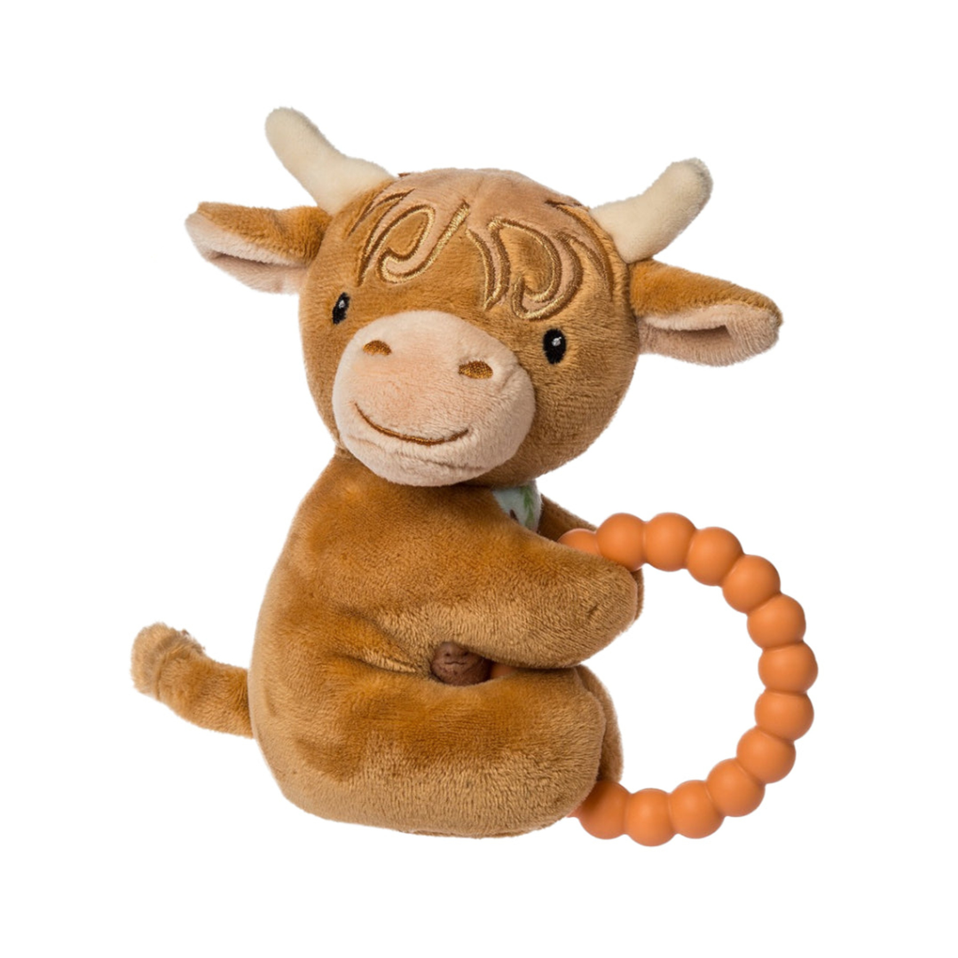 Plush toy cow with a teething ring on a white background