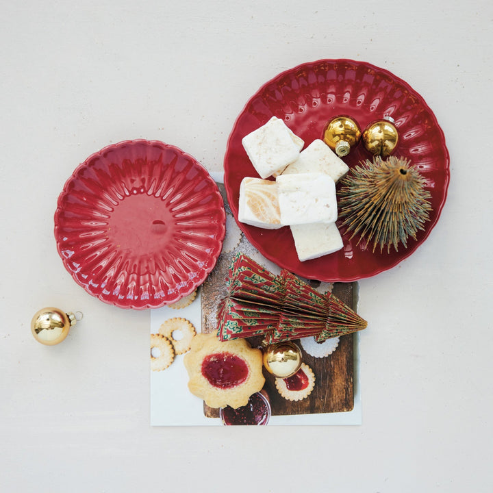Red ceramic plates with marshmallows, gold ornaments, and cookies on a white background