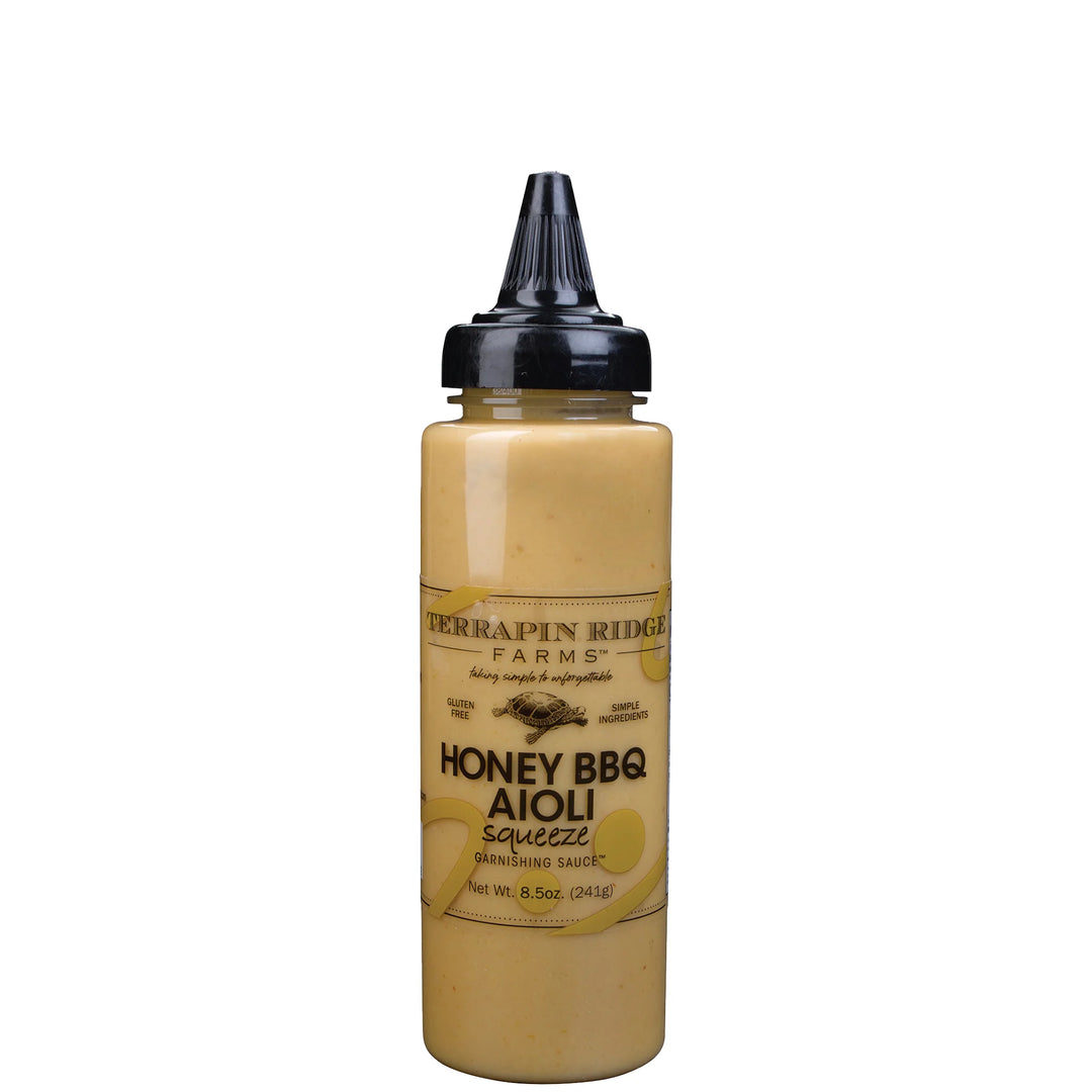 A squeeze bottle of Terrapin Ridge Farms Honey BBQ Aioli sauce, filled with a golden yellow sauce and topped with a black cap, on a white background.