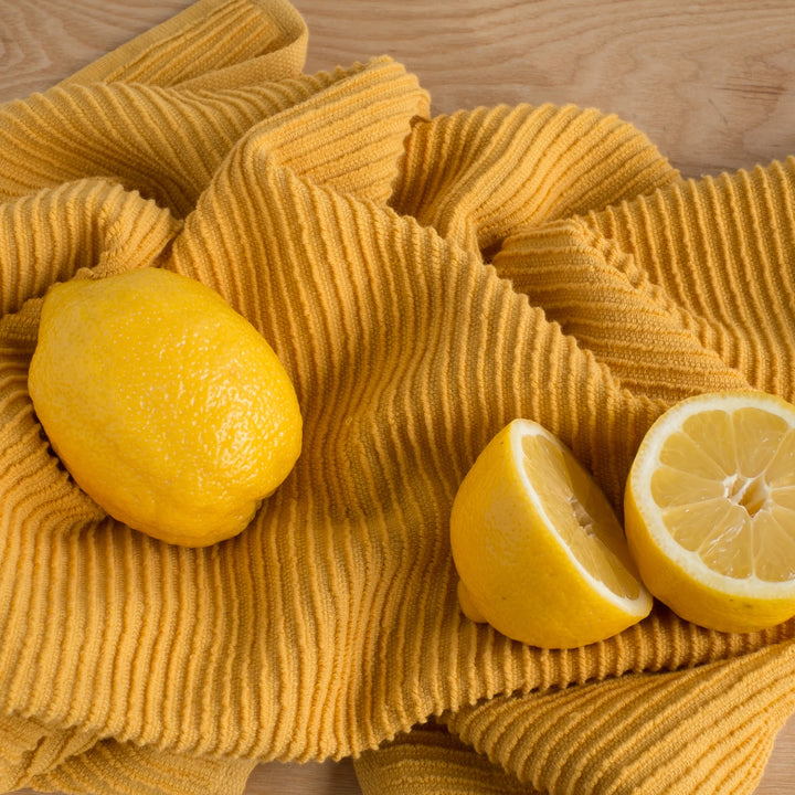 Yellow lemons on a textured yellow cloth with a wooden background