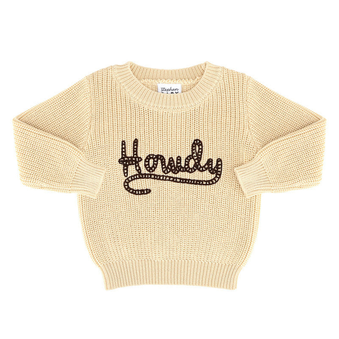 A cream-colored ribbed knit sweater with 'Howdy' written across the chest in black sequins, displayed flat against a white background.