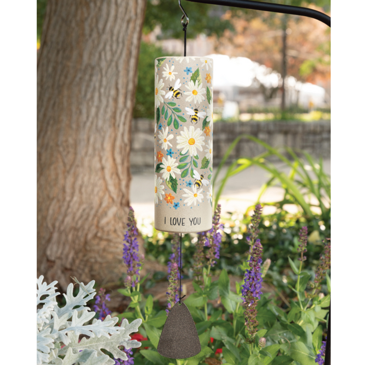 Decorative wind chime with floral design and 'I Love You' text hanging in a garden.