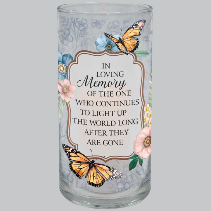 Glass candle holder with butterfly design and memorial text on a gray background