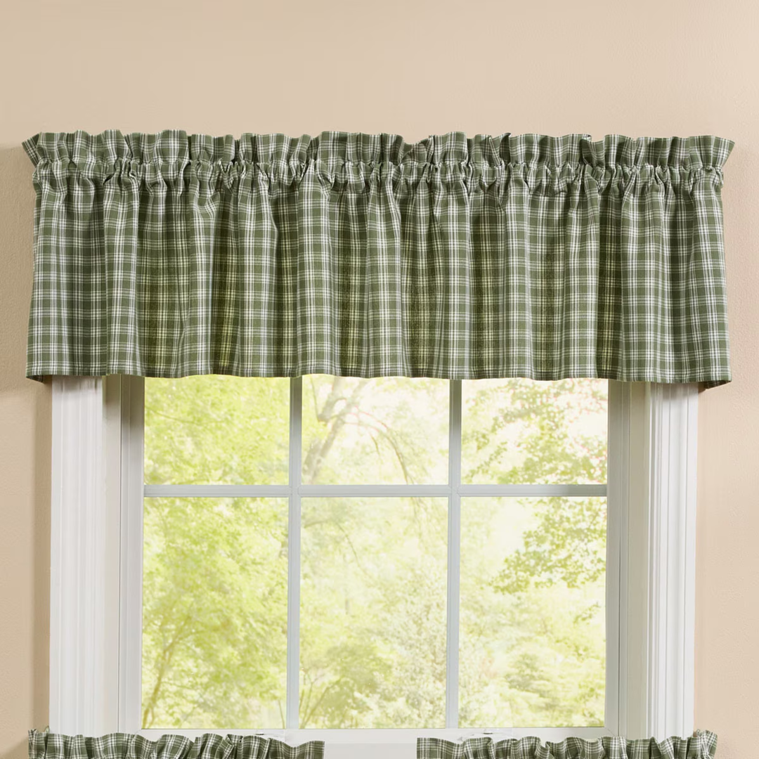 Green plaid valance on a window with a beige wall background
