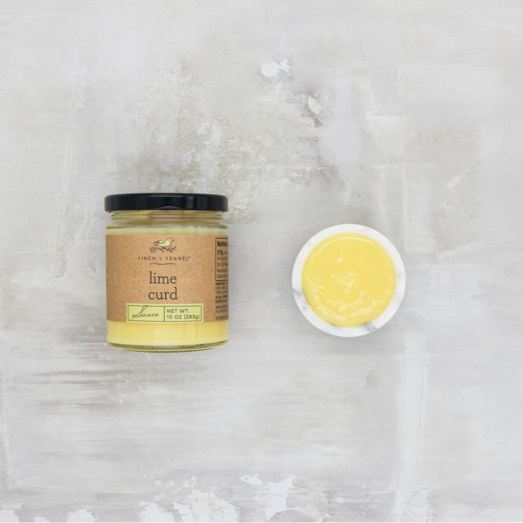 Jar of lime curd and a small bowl of lime curd on a textured white background