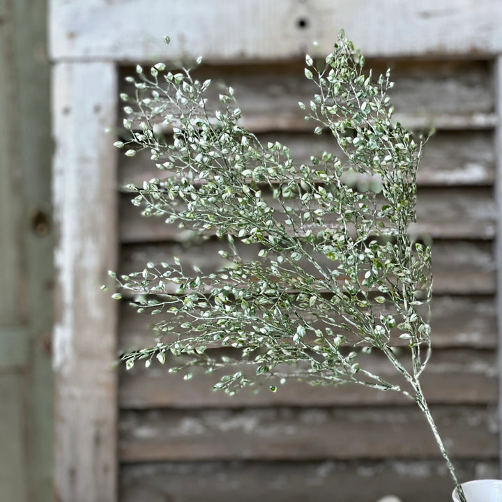 A artificial green leaves spray against a wooden backdrop
