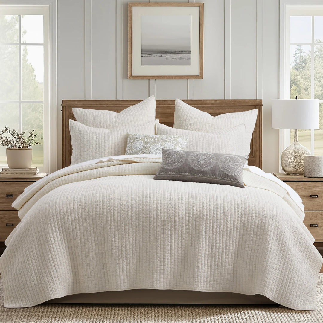 Neatly made bed with white bedding and pillows in a bedroom setting.