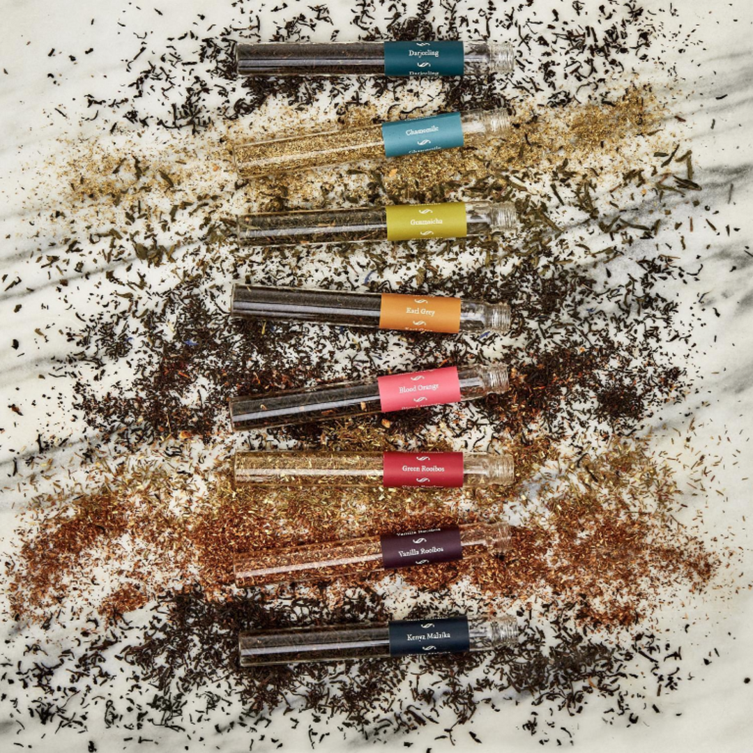 Row of small glass tubes with colorful labels on a textured surface with black and white powder.