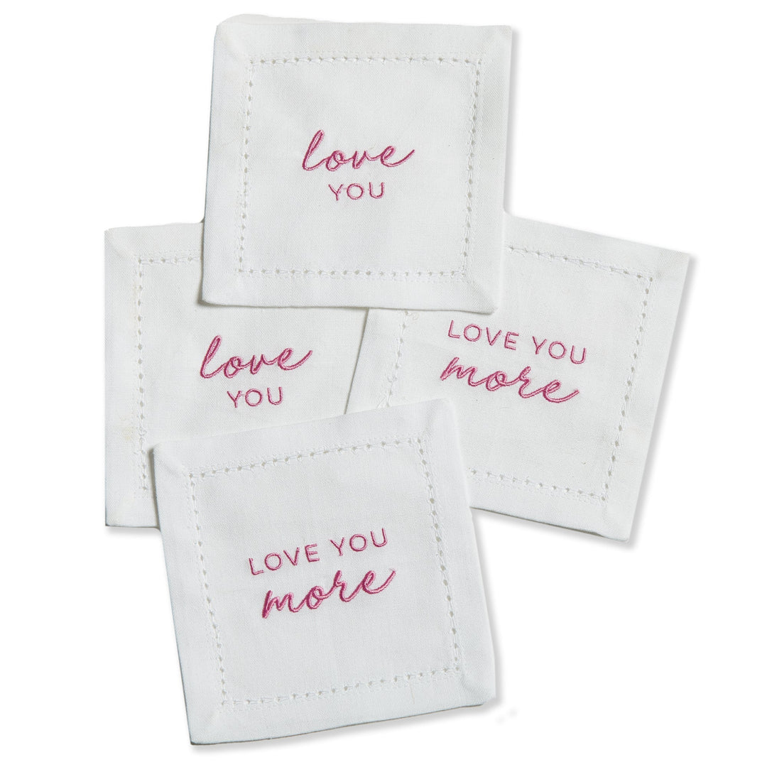 Set of white coasters with 'love you' and 'love you more' text in pink on a white background