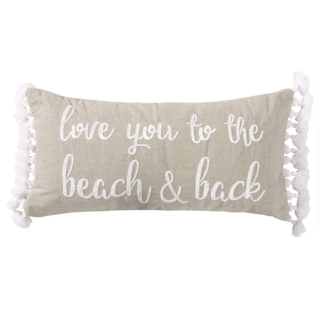 Beige pillow with 'love you to the beach & back' text and tassels on a white background