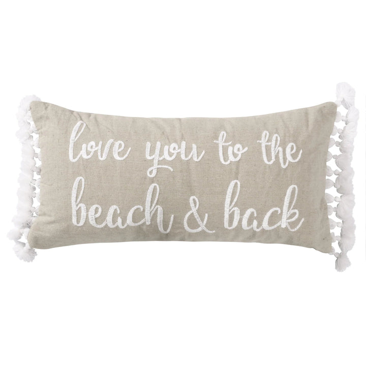 Beige pillow with 'love you to the beach & back' text and tassels on a white background