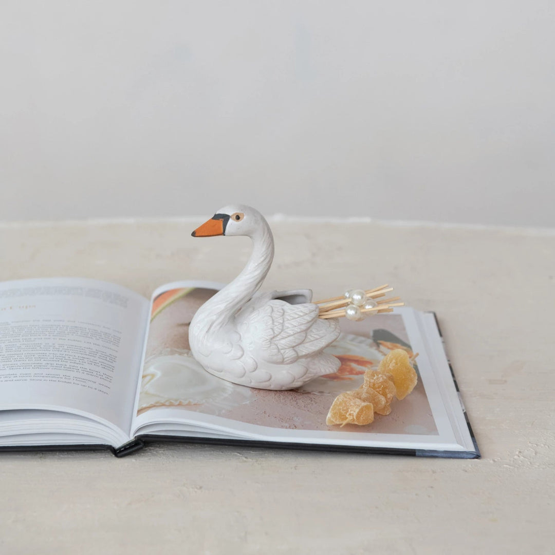 White swan figurine on an open book with a light gray background