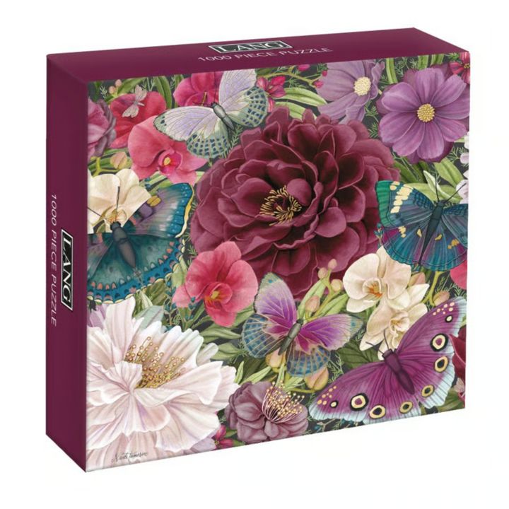 A rectangular jigsaw puzzle box with a colorful floral and butterfly illustration. The front shows large flowers in pink, purple, white, and burgundy with blue, teal, and purple butterflies among green leaves.