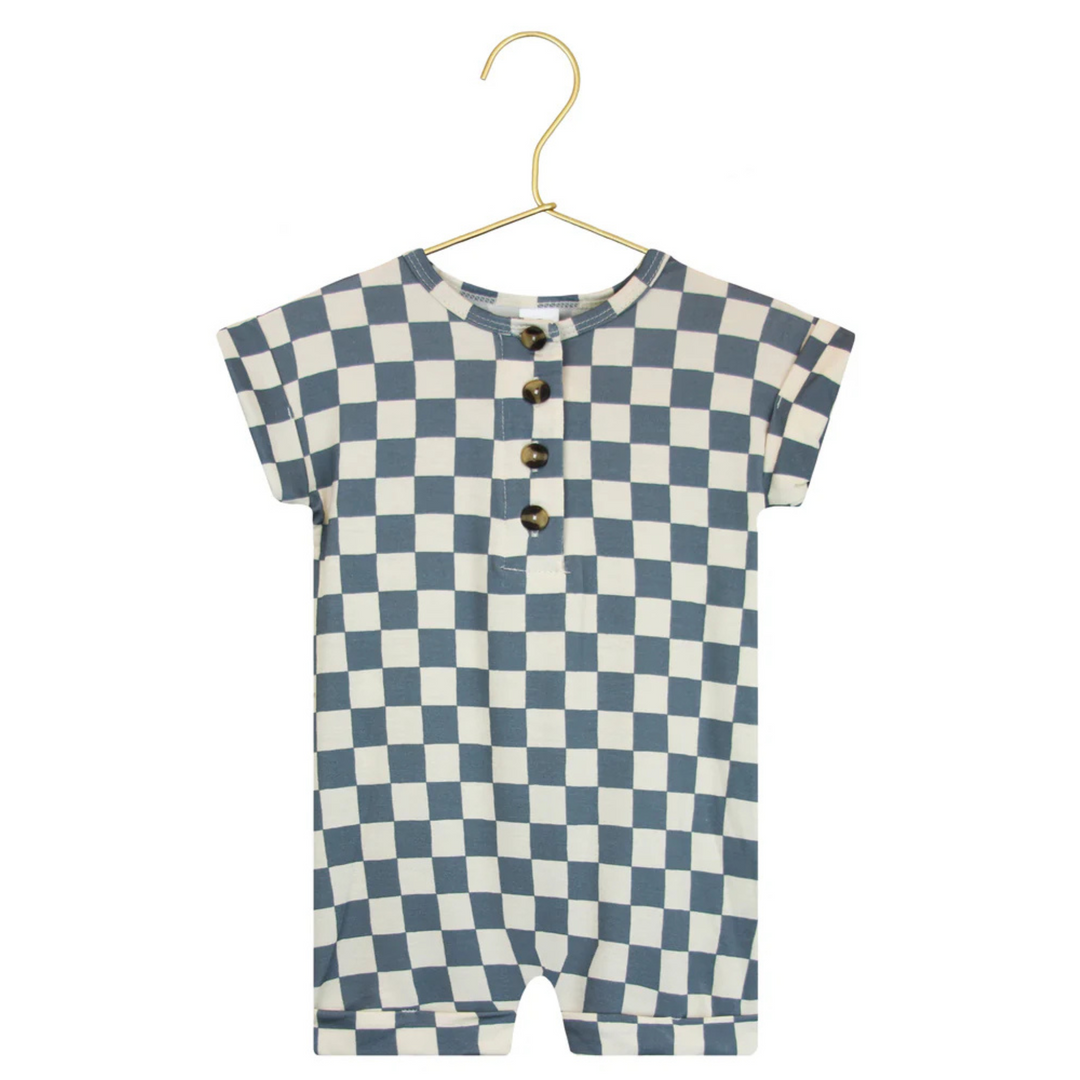 A baby short-sleeve romper with a blue and cream checkerboard pattern, featuring a three-button henley neckline, hanging on a gold hanger against a white background with a circular fabric detail inset.