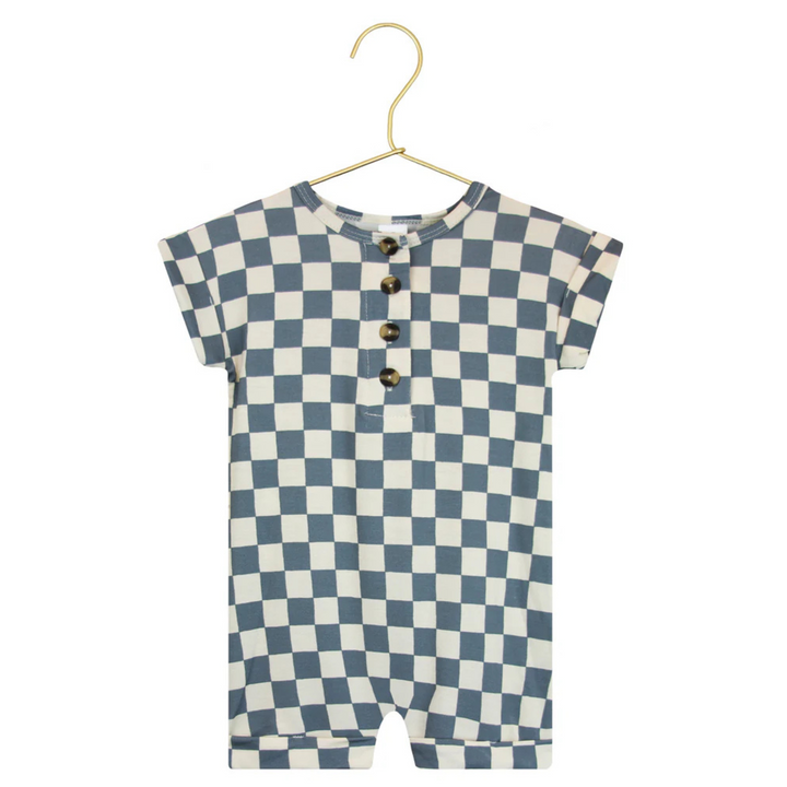 A baby short-sleeve romper with a blue and cream checkerboard pattern, featuring a three-button henley neckline, hanging on a gold hanger against a white background with a circular fabric detail inset.