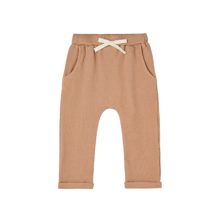 Brown waffle knit baby pants with a white drawstring on a white background