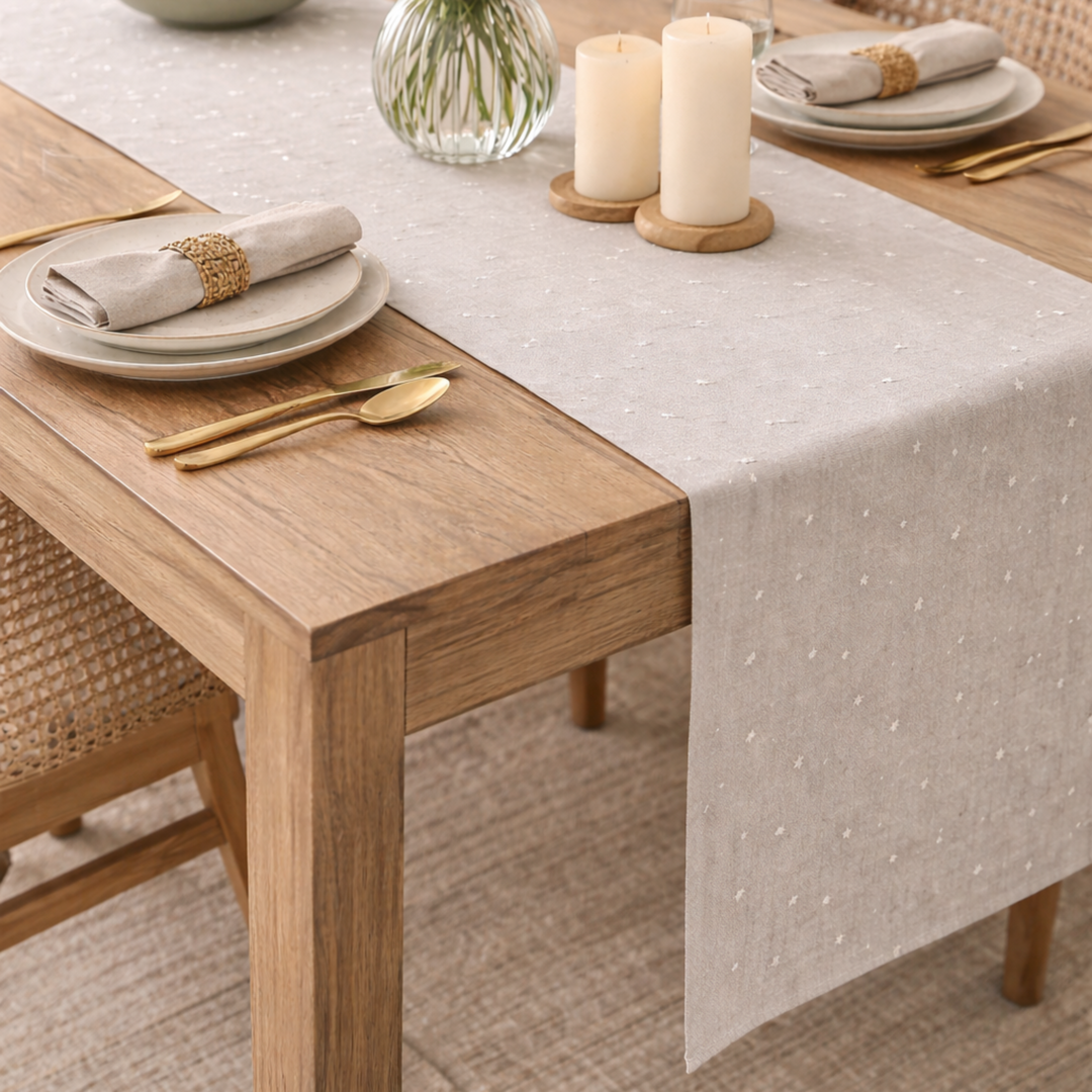 Dining table set with plates, candles, and flowers on a textured tablecloth.
