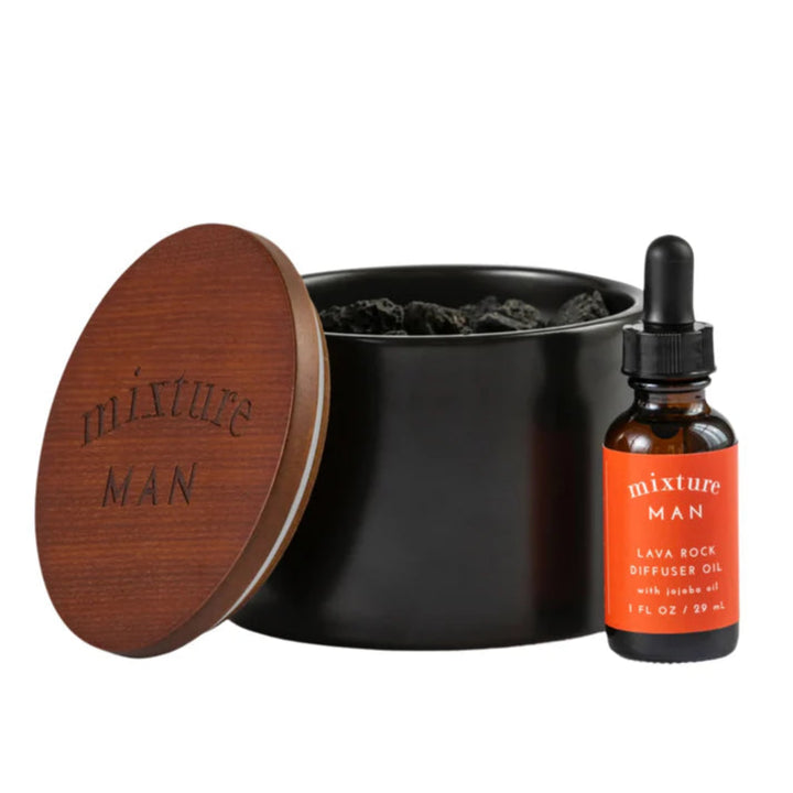 A black lava rock diffuser with a wooden lid and a dropper bottle of diffuser oil, on a white background.