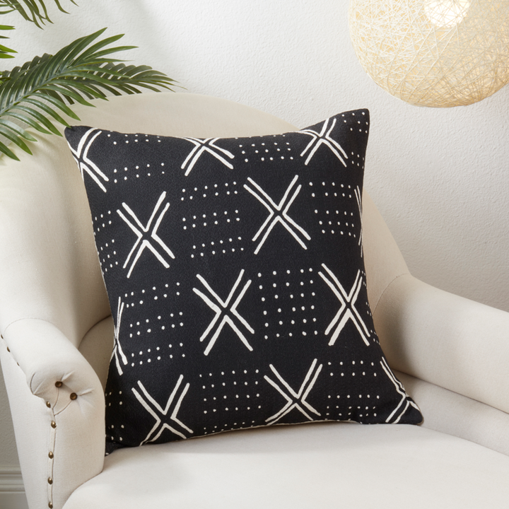 Black pillow with white geometric pattern on a white armchair