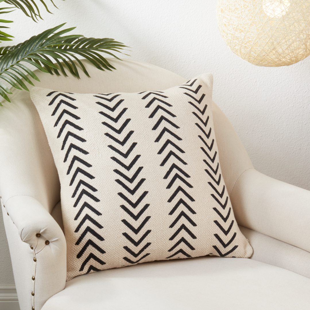 Decorative pillow with black chevron pattern on a white armchair.
