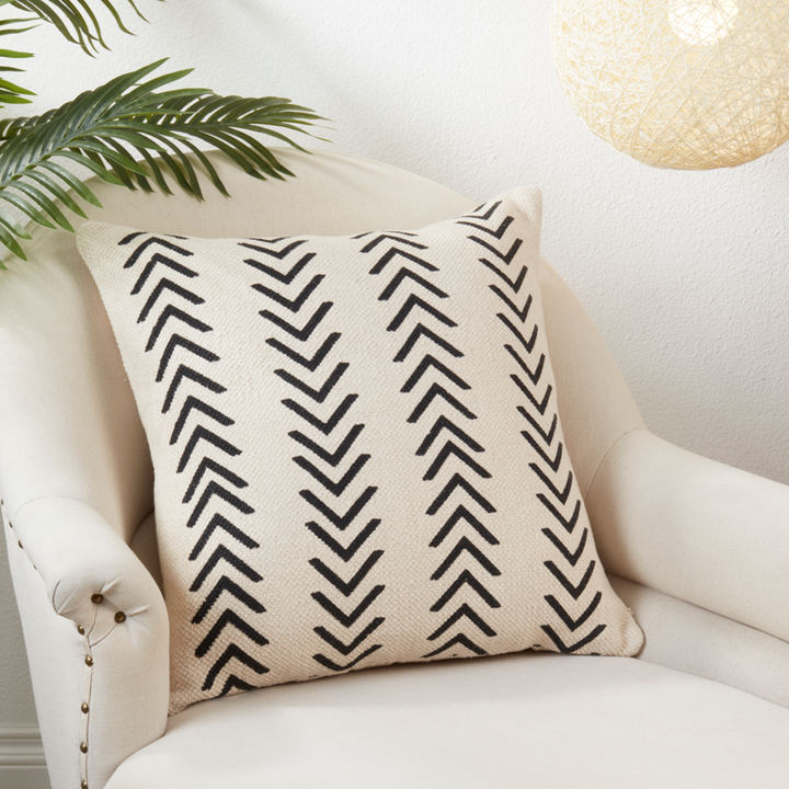 Decorative pillow with black chevron pattern on a white armchair.