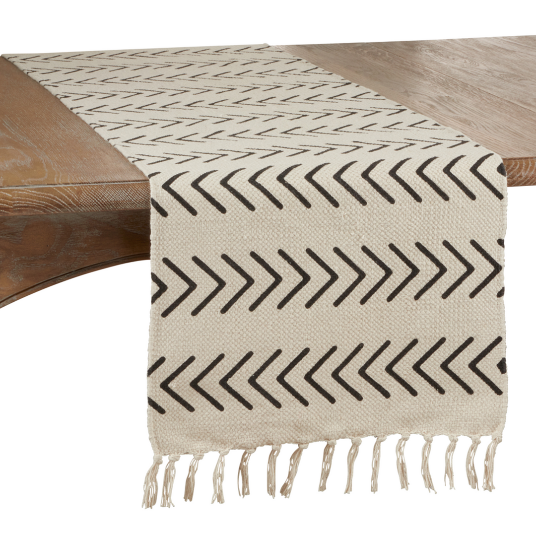 Beige table runner with black arrow pattern on a wooden table