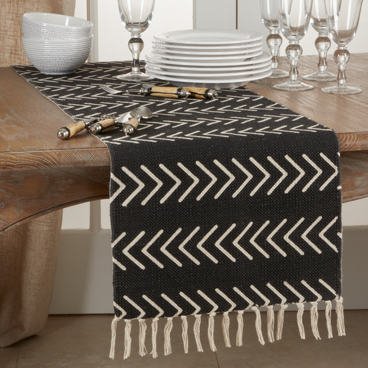 Black and white patterned table runner on a wooden table with dinnerware in the background.