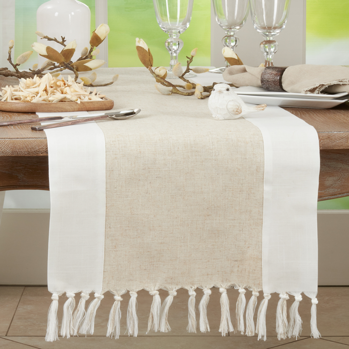 Table setting with a beige and white table runner, glasses, and decorative elements.