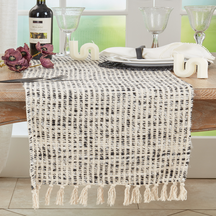 Table setting with a textured table runner, wine bottle, and glasses.