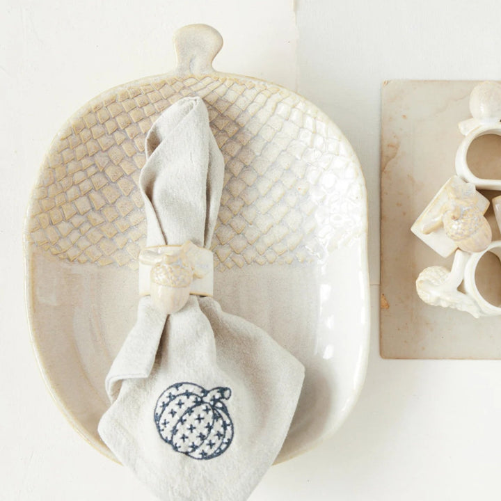 Decorative items including a woven basket, white napkin with a pumpkin design, and wooden blocks with letters on a white background.