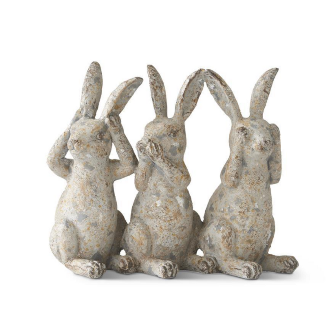 Three rustic rabbit statues on a white background