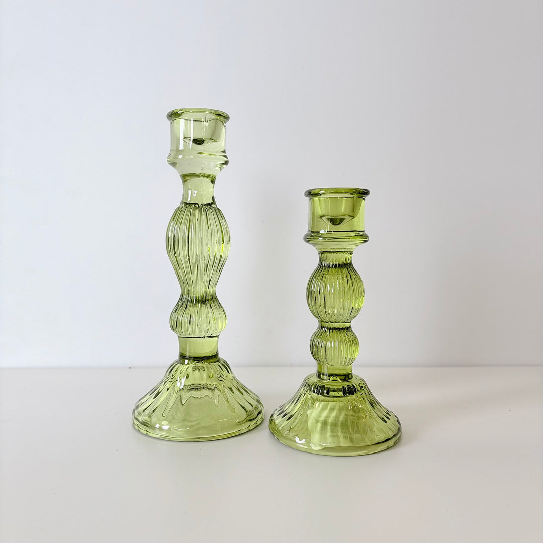 Two green glass candle holders on a white background