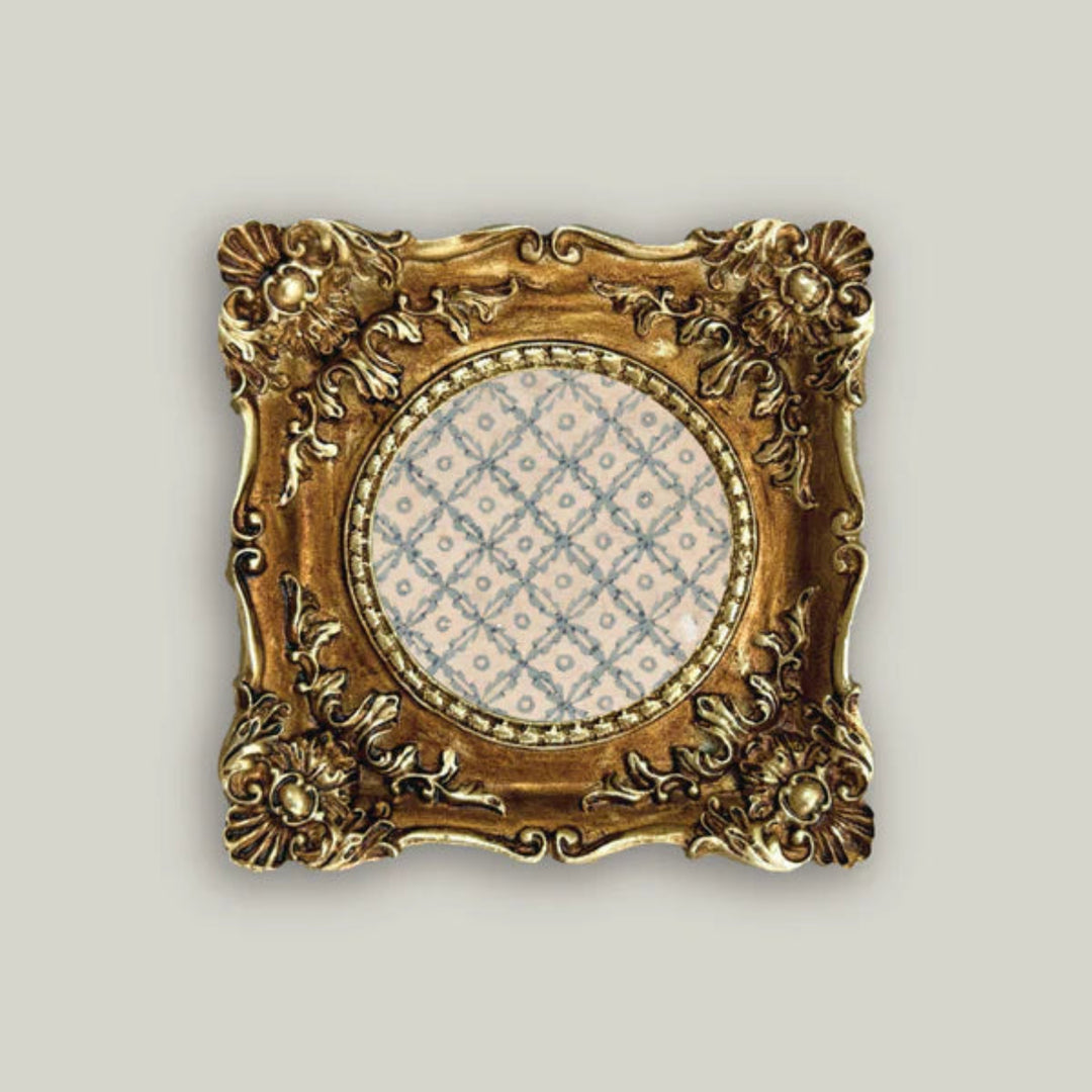 Decorative gold frame with a circular patterned center on a light gray background