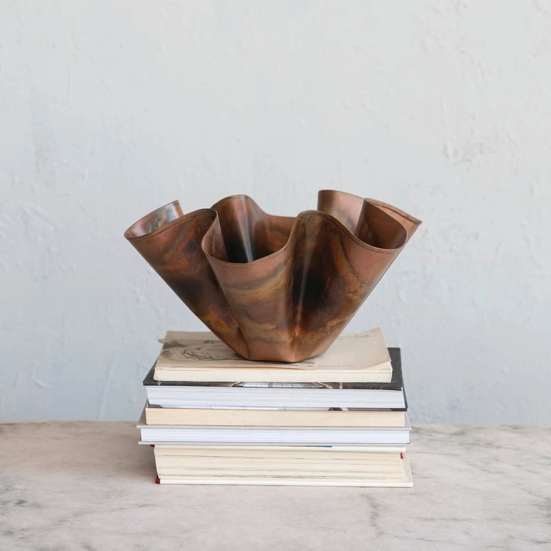 Bronze vase on a stack of books against a plain background
